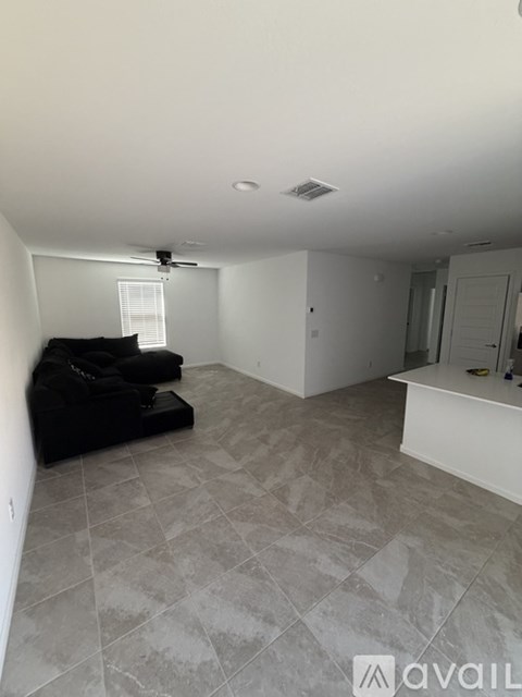 A living room with a black couch and a fan on the ceiling.