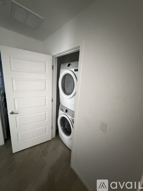 A white door is open to a laundry room with a washer and dryer.