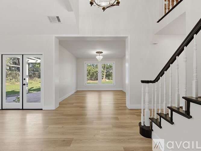 A spacious hallway with wooden floors and white walls.