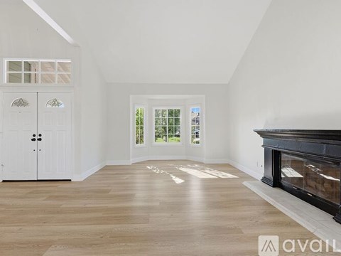 A spacious living room with a fireplace and a large window.