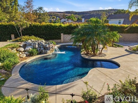 A pool surrounded by a garden with a palm tree.