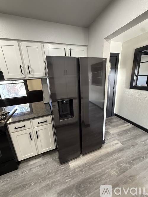 A kitchen with a black fridge and white cabinets.