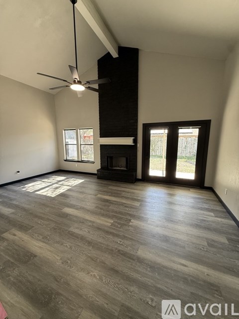 A spacious room with a fireplace and a ceiling fan.