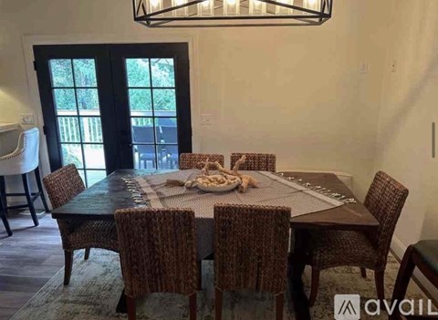 A dining room with a table set for six and a chandelier hanging from the ceiling.