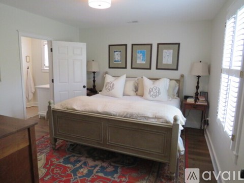 A bedroom with a large bed and a rug on the floor.