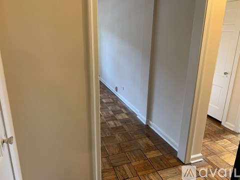 A hallway with a wooden floor and white walls.