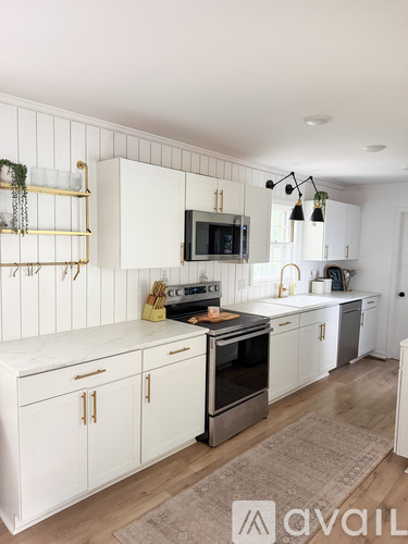 A kitchen with white cabinets and a wooden floor.
