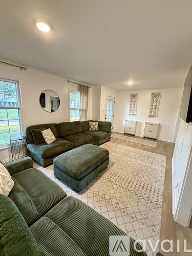 A living room with a green couch and ottoman.