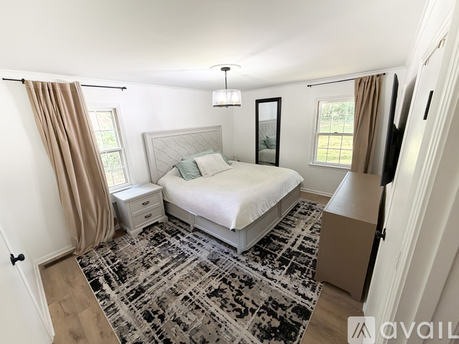 A bedroom with a large bed and a rug on the floor.