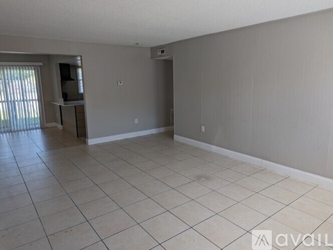 A spacious room with beige walls and tile flooring.