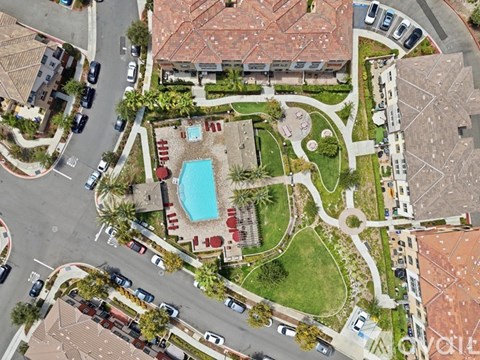 A bird's eye view of a residential area with a swimming pool and a green lawn.