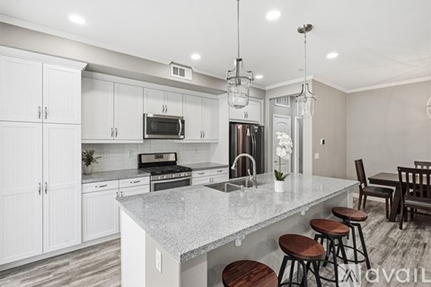 A kitchen with white cabinets and a marble countertop.