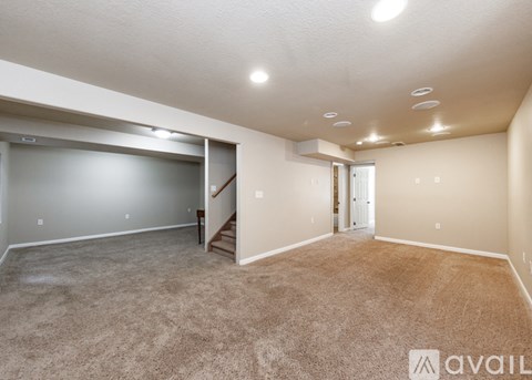 A spacious room with a carpeted floor and a staircase leading to another room.