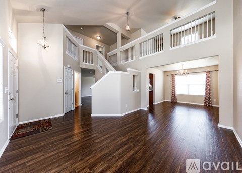 A spacious living room with hardwood floors and a staircase leading to the upper level.
