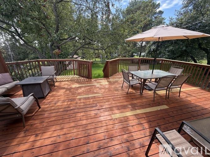 A wooden deck with chairs and an umbrella.