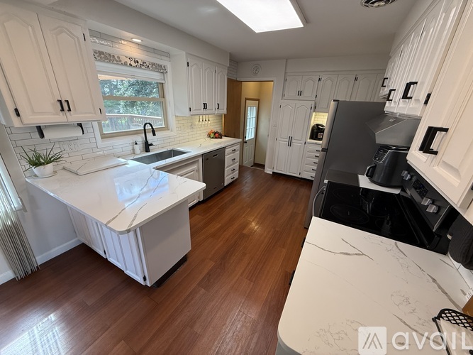A kitchen with white cabinets and a marble countertop.