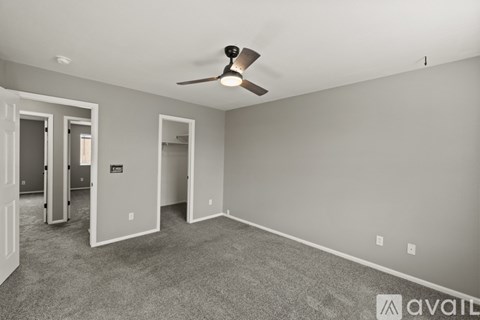 A spacious room with a ceiling fan and carpeted floor.