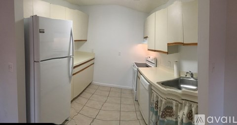 A kitchen with a refrigerator, sink, and cabinets.