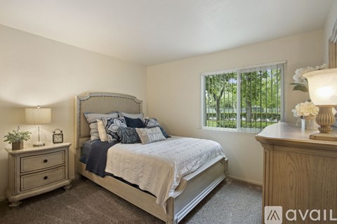 A bedroom with a bed, nightstand, and window.
