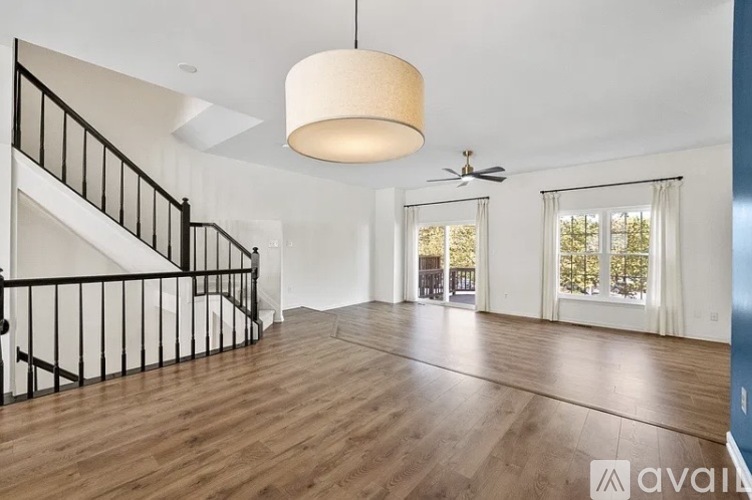 A spacious living room with wooden floors and a staircase.