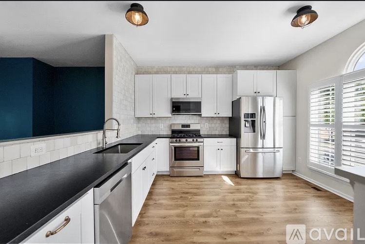 A kitchen with white cabinets and a black countertop.
