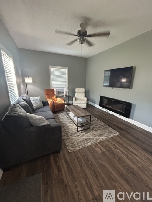 A living room with a grey couch, a black coffee table, a fireplace, and a television.