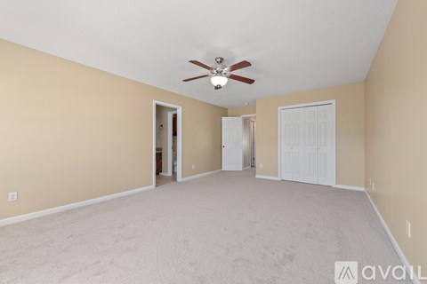 A spacious room with a ceiling fan and carpeted floor.