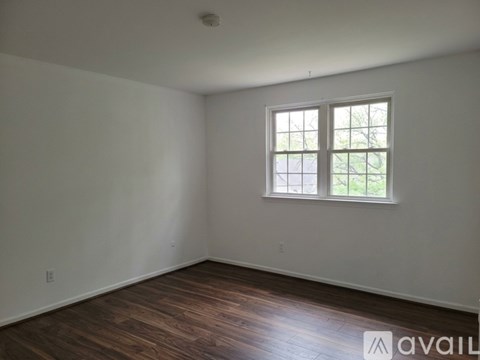 A room with a window and wooden flooring is available for rent.