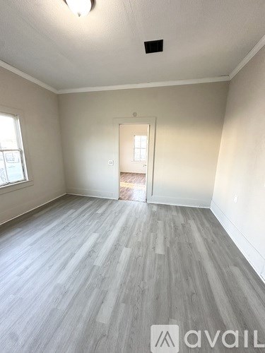 A room with a wooden floor and a doorway leading to another room.