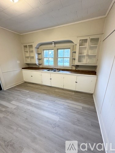 A kitchen with white cabinets and a window.