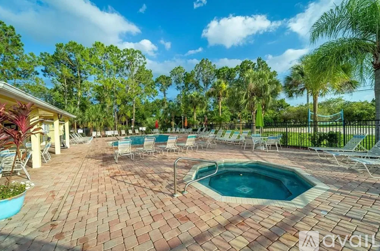 A pool surrounded by chairs and trees.