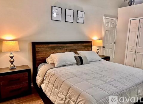 A bedroom with a bed, two lamps, and two pictures on the wall.