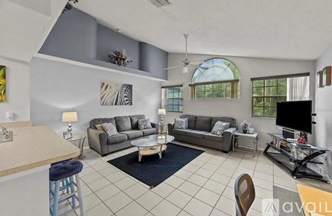 A living room with a grey couch and a white ceiling fan.