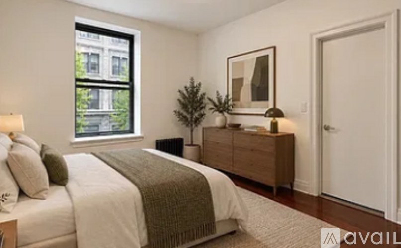 A bedroom with a bed, a dresser, and a window overlooking a building.