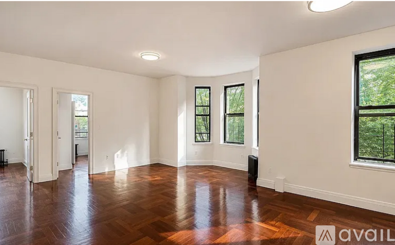 A spacious room with wooden floors and large windows.