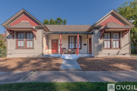 A two-story house with a red door and red window frames.