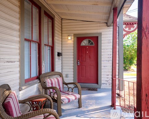 A red door is on the right side of a white house.