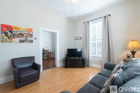 A living room with a black leather chair and a poster on the wall.