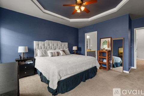 A bedroom with a large bed and a ceiling fan.
