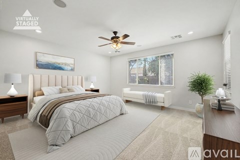 A bedroom with a large bed and a ceiling fan.