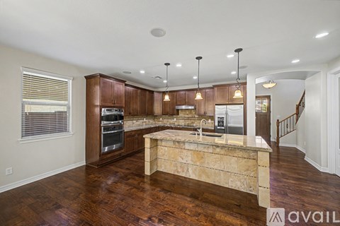 A kitchen with wooden cabinets and a marble island.