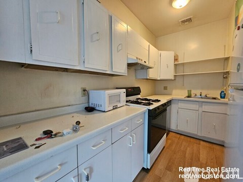 A kitchen with white cabinets and appliances.
