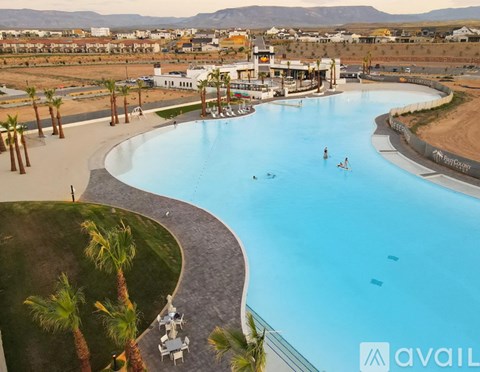 A large outdoor swimming pool surrounded by palm trees and a few people swimming.