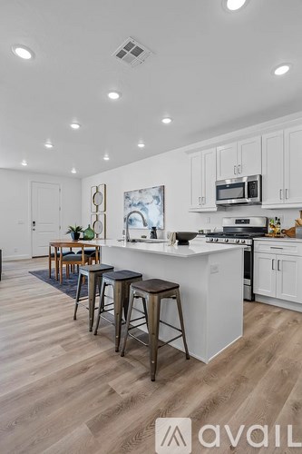 A kitchen with white cabinets and a white island with a painting on the wall.