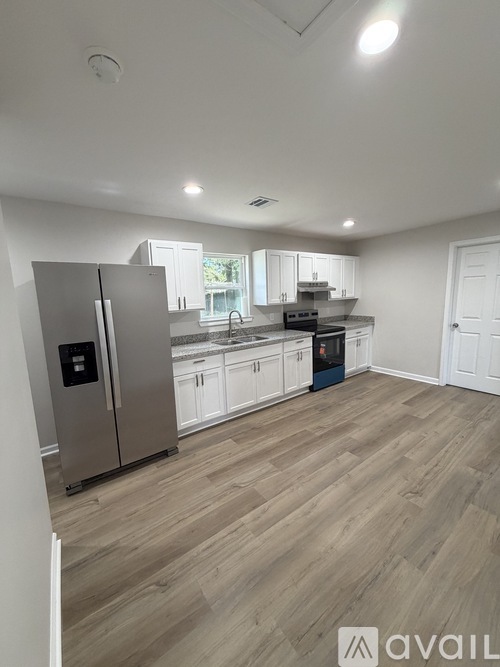 A kitchen with a refrigerator, cabinets, and a countertop.