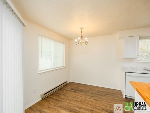 A well-lit, empty room with wooden floors and a chandelier.