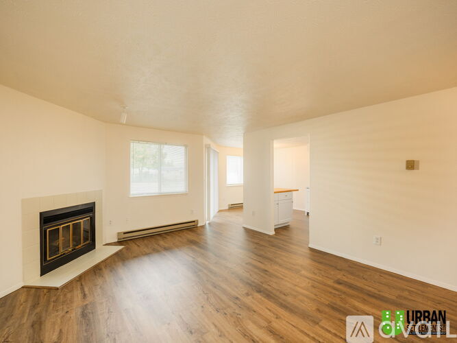 A spacious room with a fireplace and wooden floors.