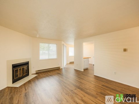 A spacious room with a fireplace and wooden floors.