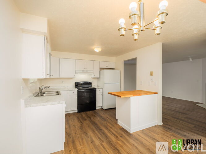 A kitchen with white cabinets and a wooden island.