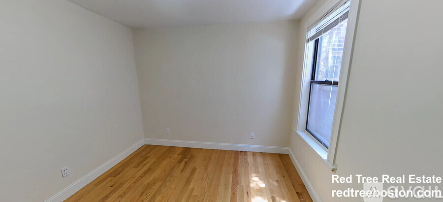 A room with wooden flooring and a window.